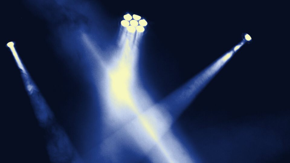 Scheinwerfer werfen Lichtstrahlen durch den Nebel über einer Bühne